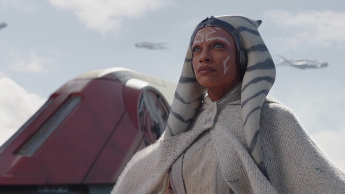 Ahsoka in all white stands outside a ship with purrgil flying arounf