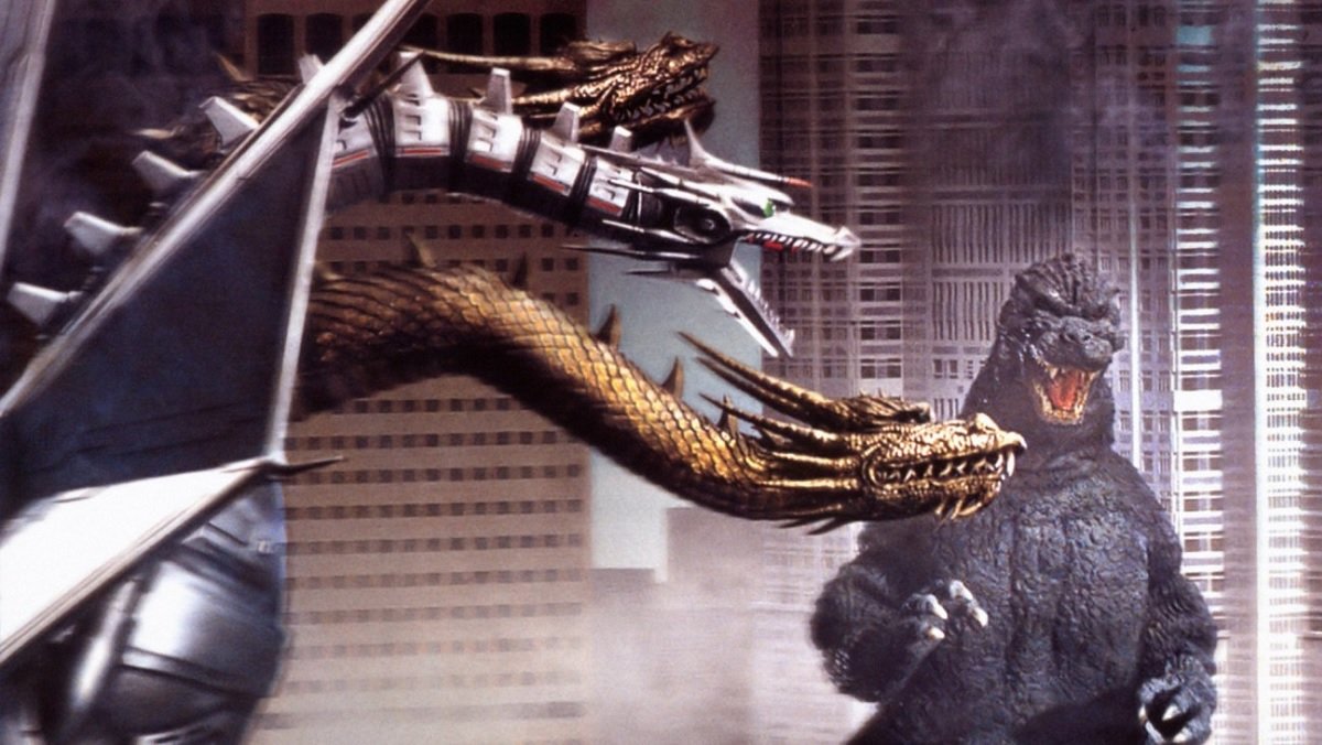 Godzilla fights against the three-headed King Ghidorah (one head is mechanical) in front of a massive cityscape.
