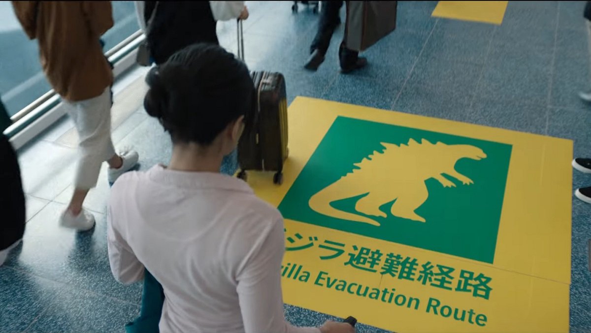 Someone looks at a floor sign for Godzilla Evacuation Zone from Monarch: Legacy of Monsters.