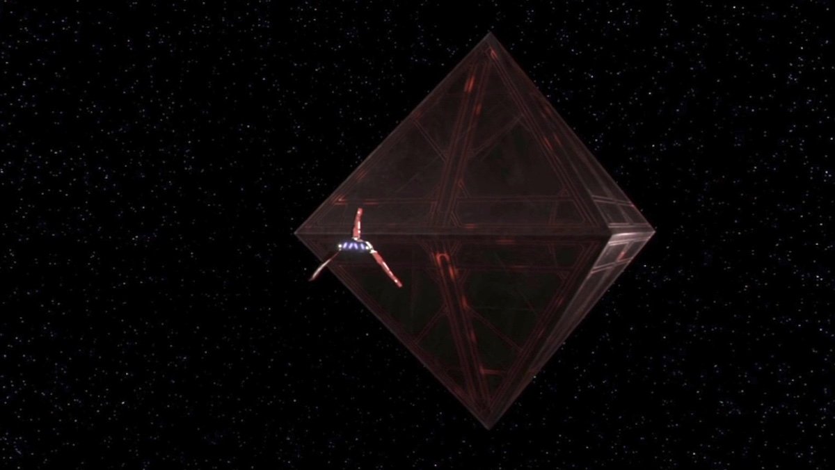 A space ship flies towards a giant black and red monolith that resembles two pyramids stacked opposite one another on The Clone Wars
