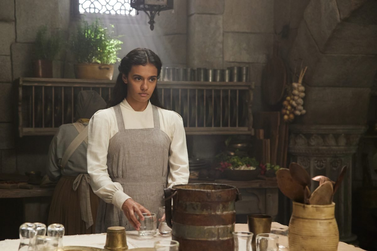 Egwene al'Vere in a kitchen in white and a gray apron in The Wheel of Time season 2